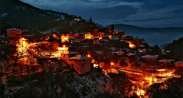 http://Panoramic%20night%20view%20of%20a%20city%20in%20Kosovo%20illuminated%20by%20warm%20lights%20with%20surrounding%20hills%20in%20the%20background