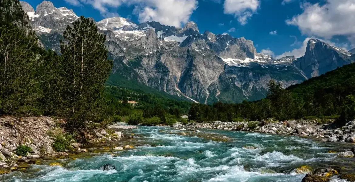 http://Panoramic%20view%20of%20Valbona%20River%20flowing%20through%20a%20wide%20mountain%20valley%20surrounded%20by%20alpine%20peaks%20in%20northern%20Albania